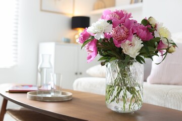 Bouquet of beautiful peonies and water on coffee table indoors, closeup. Interior design