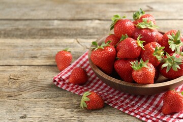 Fresh ripe strawberries in bowl on wooden table, closeup. Space for text