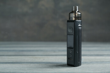 One electronic smoking device on wooden table against grey background, closeup. Space for text