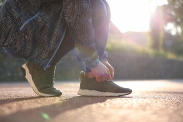 Woman tying shoelace of sneaker at stadium, closeup. Space for text