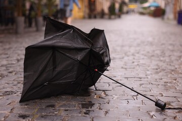 Broken umbrella on wet pavement outdoors, closeup
