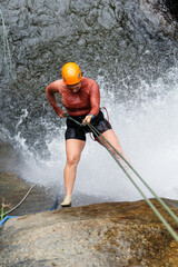 Female canyoneer rappelling down a waterfall, demonstrating skill and courage in extreme sport