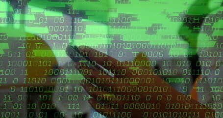 Holding smartphone with adult hand showing binary code overlay at home office, with potted plant