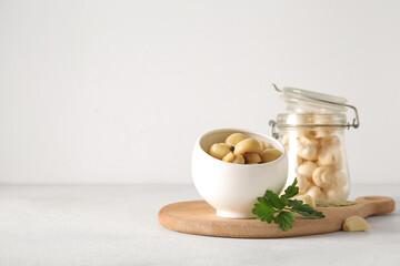 Bowl with canned mushrooms on light background