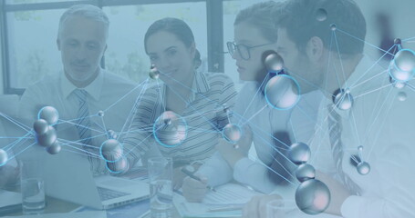 Reviewing laptop charts colleagues wearing formal attire in conference room, with molecular overlay