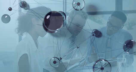 Collaborating team consulting paperwork and using tablet in conference room with network overlay