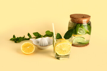 Glass of cold mojito and juicer on color background
