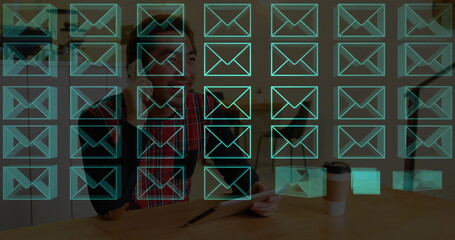 Using stylus on tablet barista wearing apron, earbuds in café, showing envelope overlays coffee cup