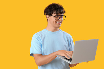 Male programmer working with laptop on orange background
