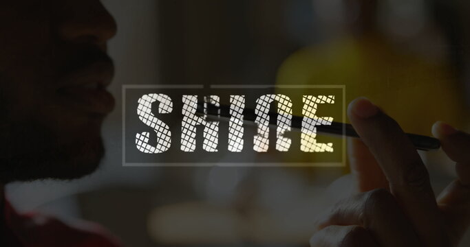 Holding stylus, side-profile silhouette man drawing SHINE overlay on tablet in studio, red shirt