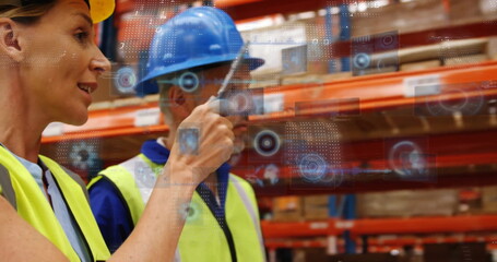 Pointing woman in yellow hard hat interacting in warehouse, with holographic display, copy space