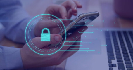 Office worker wearing blue shirt holding smartphone at desk, showing laptop, digital padlock