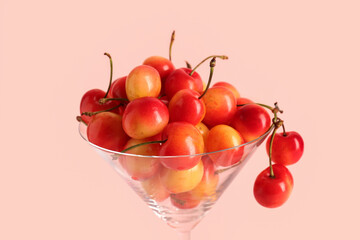 Glass with sweet yellow cherries on pink background