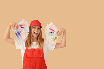 Happy female decorator with color samples on beige background