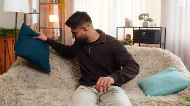 Indian man at home frantically checks pockets and under pillows for lost keys with anxious face. Arabian guy feels stress and confusion, then finally relaxes with relief when he finds them again.