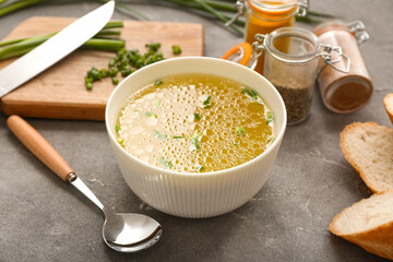 Bowl of tasty vegetable broth on grey background