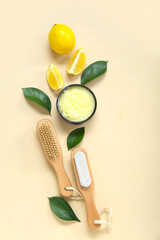 Bowl of lemon body scrub with massage brushes on beige background