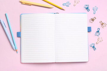 Notebook with different stationery supplies on pink background