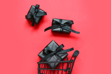 Shopping cart with black gift boxes on red background. Black Friday concept