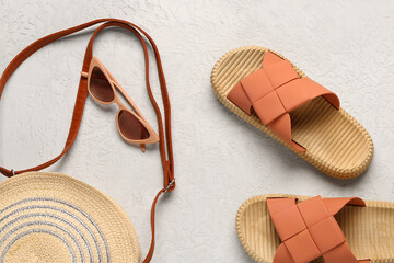 Female stylish flip flops with beach accessories on light background