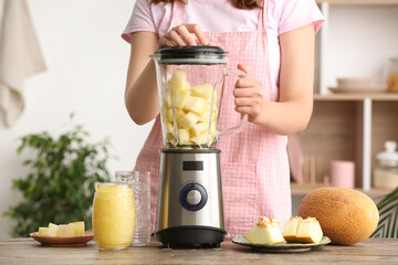 Woman preparing tasty melon smoothie at table in kitchen