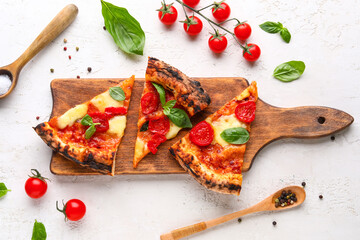 Wooden board with slices of tasty pizza Margarita and fresh tomatoes on white background