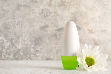 Deodorant and chamomile flower on table against grunge background