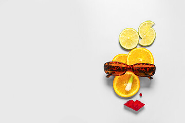 Funny face made of citrus fruits and stylish sunglasses on light background