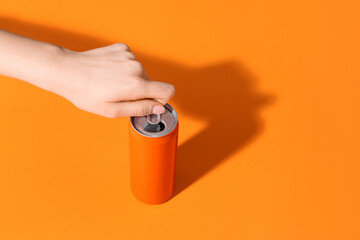 Obraz na płótnie Canvas Female hand opening soda can on orange background