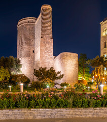 Maiden Tower, or Qiz Qalasi, illuminated at night in Baku, Azerbaijan, with a garden foreground