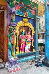 Obraz premium Colorful statues of Hindu deities at the entrance of a temple in Batu Caves, Kuala Lumpur, Malaysia. A No Shoes sign is visible with sandals left by worshippers