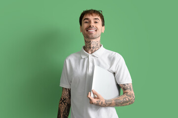 Happy young man with modern laptop on green background