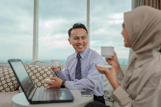 Two professionals share a warm moment over coffee in a stylish office, enjoying conversation