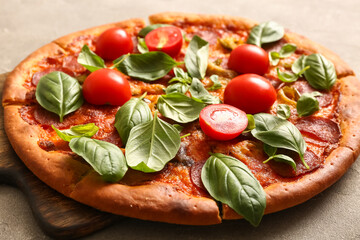 Wooden board of delicious Pepperoni pizza with tomatoes and basil on grey background