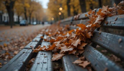 Dry curled brown leaves on an old bench with a blurred urban park background, melancholic autumn mood"