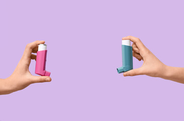 Child's hands with asthma inhalers on lilac background