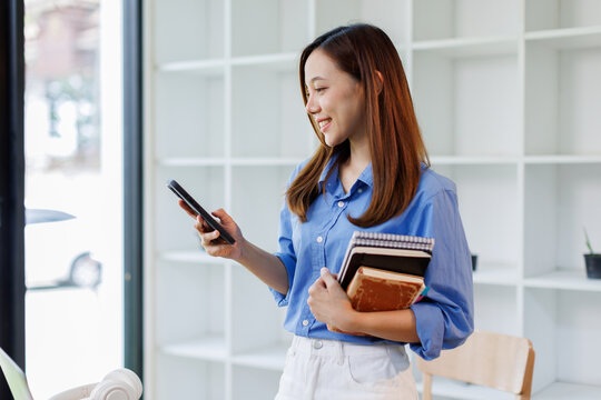 Portrait of smiling smart teenage girl holding phone looking at camera standing in modern classroom, copy space. Back to school, education concept
- Powered by Adobe