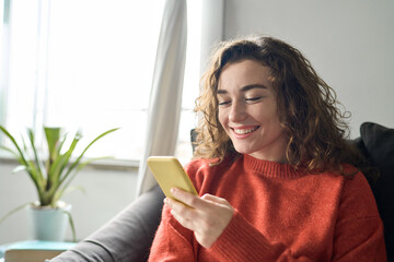 Happy girl holding smartphone, looking at cellphone doing online shopping in mobile apps. Smiling...