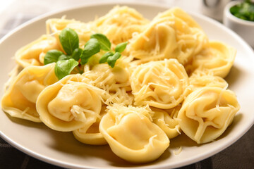 Plate of boiled dumplings with cheese and basil on grey background, closeup
