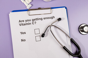 A white paper asks a critical health question about vitamin C intake, placed beside a stethoscope...