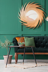 Interior of stylish living room with green sofa, table and golden mirror