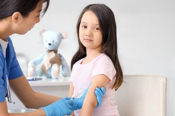 Little Asian girl receiving vaccine in clinic