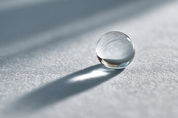 minimalist photograph of crystal clear water droplet resting on light gray background