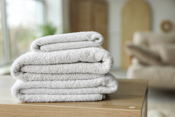 Stack of clean soft towels on wooden table at home, closeup
