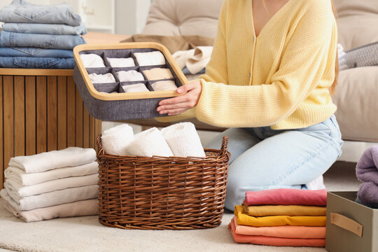 Woman with different clean clothes sitting on floor at home