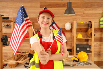 Young female carpenter with USA flags in workshop. Labor Day celebration