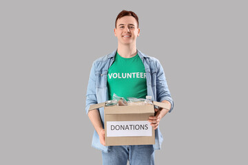 Male volunteer with donation box on light background