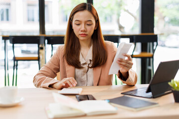 asian young woman hand checking list with bill for calculate accounting expense credit card payment...