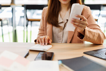 asian young woman hand checking list with bill for calculate accounting expense credit card payment...