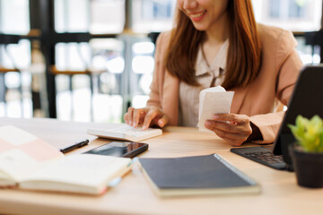 asian young woman hand checking list with bill for calculate accounting expense credit card payment...